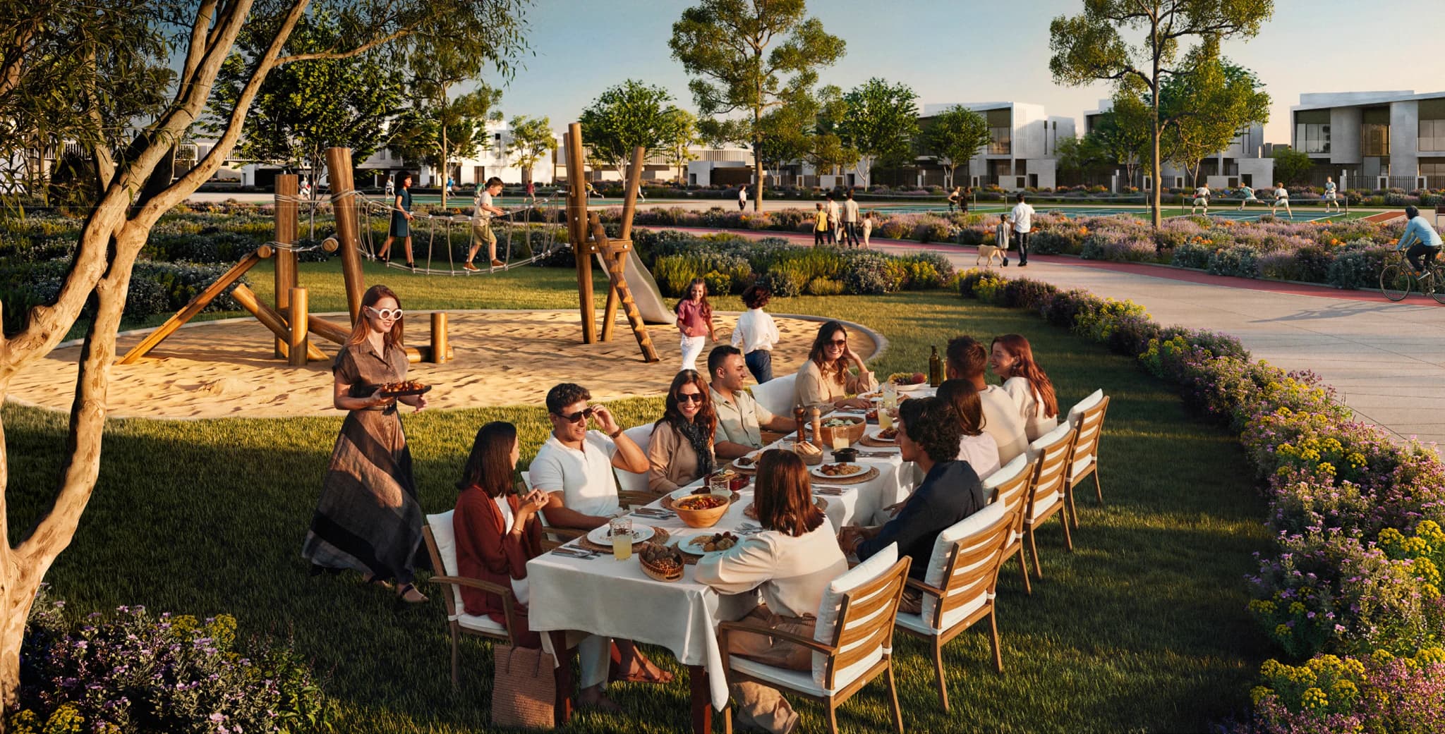 Families gathering over a long outdoor table in the green spaces at Talay